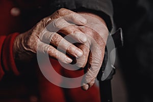 Hands of an old woman and man holding cane, skin wrinkled