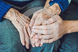 Hands of an old woman and a young man. Caring for the elderly. c