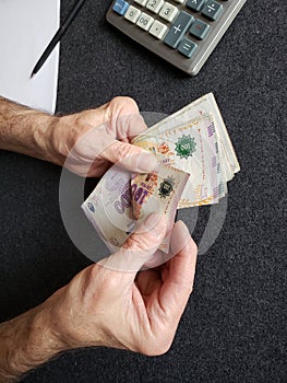 hands of an older man counting argentine banknotes