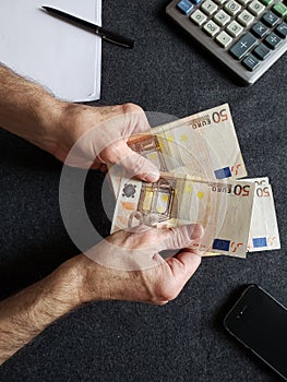 hands of an older man counting european banknotes
