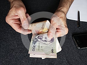 hands of an older man counting uruguayan banknotes