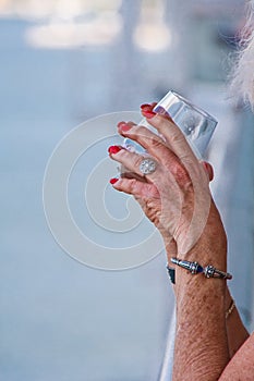 Hands of Older Woman Holding Drink On Coastal Balcony photo