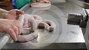 Hands of operators filling and forming sausages at food production factory. Sausage production line. Sausage factory