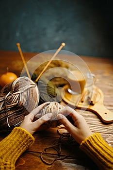 Hands in orange sweater with yarn, knitting needles and coffee.