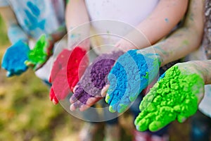 Hands Palms of young people covered in purple, yellow, red, blue Holi festival colors .