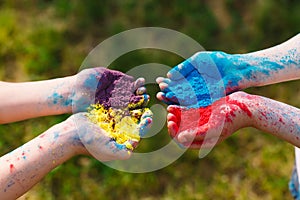 Hands Palms of young people covered in purple, yellow, red, blue Holi festival colors .