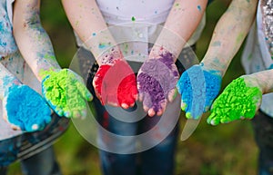 Hands Palms of young people covered in purple, yellow, red, blue Holi festival colors 