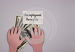 Hands of paper holding money and the inscription unemployment benefit