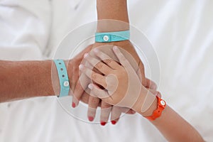 Hands of parents and child with bracelet are joined together