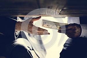 Hands passing money under table corruption bribery photo