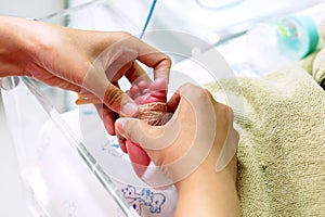 Hands of pediatric nurse using medical adhesive plaster stick and strap to measure oxygen in the blood and see the oxygen value