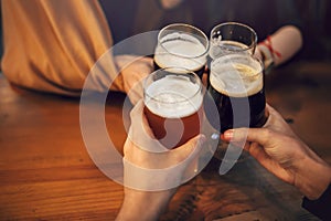 Hands of people holding beer and cheering in brewery pub. people