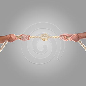 Hands of people pulling the rope on a gray background. Competition concept