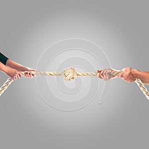 Hands of people pulling the rope on a gray background. Cooperation concept