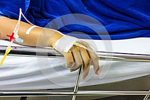 Hands of people a sick loved ones lying on a bed in the hospital.