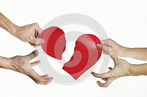 The hands of people tearing the heart apart. Valentine`s day concept. Torn heart. On isolated background