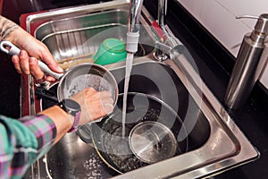 hands of a person cleaning the dishes and pans