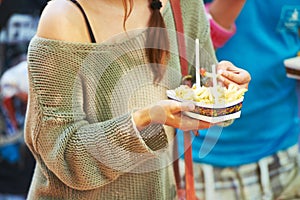 Hands, person and eating french fries outdoor, delicious snack and tasty cuisine for nutrition in summer. Fast food