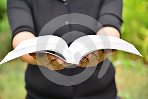 Hands of person hold the book on nature background