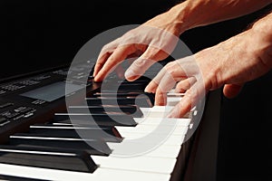 Hands of pianist playing the electronic organ on black background