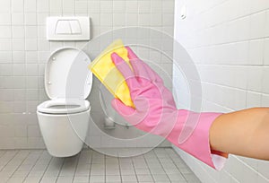 Hands in pink gloves clean the toilet