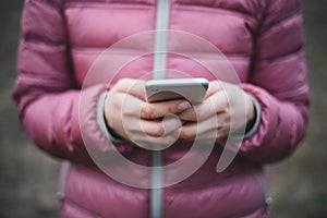 Hands in pink jaket holding while mobile phone