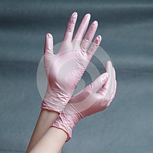 Hands in pink nitrile gloves on a gray background with a gradient
