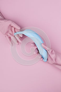 Hands in pink rubber gloves holding blue painted banana