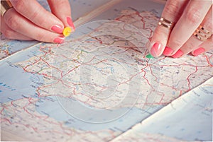 Hands pinning travel destination points on map, filtered photo