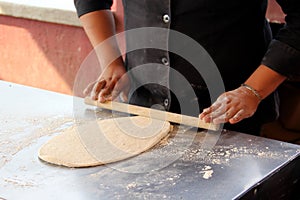 Hands of pizza maker man kneads dough, prepares and shapes for pizza base with rolling pin and flour