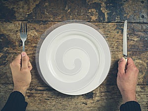 Hands with plate, knife and fork