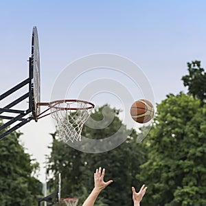 Hands of player throwing basketball ball into basket. Street basketball game. Basketball shield, Basket and ball on