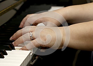 Hands playing the piano on black and white keys