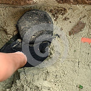Hands of a plumber close-up near a sewer pipe covered with sand. Plumber installs a reinforced orange sewer pipe during