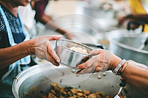 The hands of the poor handed a plate to receive food from volunteers to alleviate hunger, the concept of helping the homeless photo