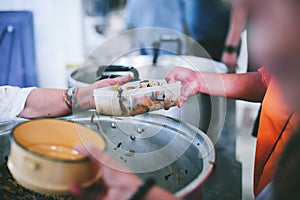 The hands of the poor handed a plate to receive food from volunteers to alleviate hunger, the concept of helping the homeless