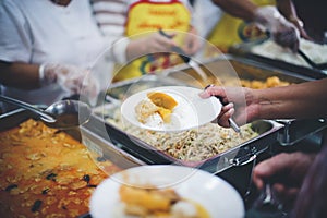 The hands of the poor handed a plate to receive food from volunteers to alleviate hunger, the concept of helping the homeless