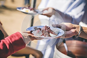 The hands of the poor handed a plate to receive food from volunteers to alleviate hunger, the concept of helping the homeless