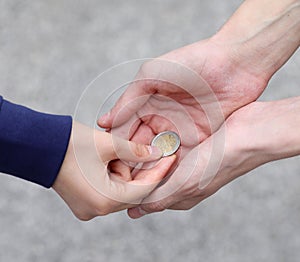 Hands of the poor man accepting the alms of a coin from a girl