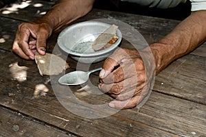 Hands the poor old man& x27;s, piece of bread and empty bowl on wood