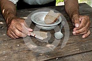 Hands the poor old man& x27;s, piece of bread and empty bowl on wood