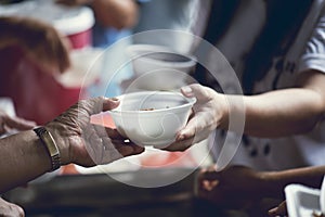 Hands of the poor receive food from the donor`s share. poverty concept