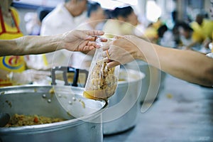 Hands of the poor receive food from the donor`s share. poverty concept