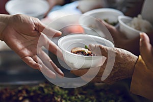 Hands of the poor receive food from the donor`s share. poverty concept photo