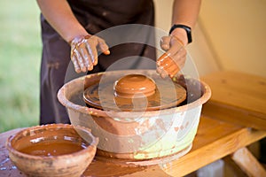 Hands of potte makes pottery dishes on potter`s wheel. Sculptor in workshop makes clay product