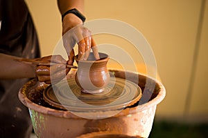 Hands of potte makes pottery dishes on potter`s wheel. Sculptor in workshop makes clay product