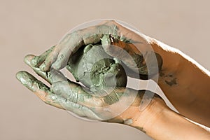 Hands of a potter with blue clay