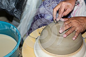 Hands of a potter, creating an bowl on the circle