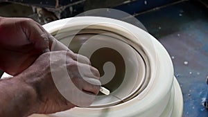 Hands of a potter, creating a bowl using a die, ceramic polishing process