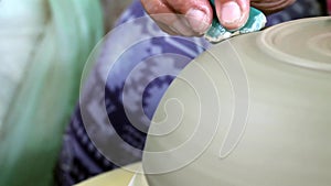 Hands of a potter, creating a bowl using a die, ceramic polishing process